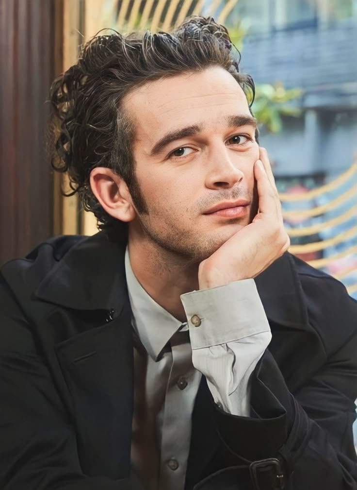 a man sitting at a table with his hand on his chin and looking off to the side