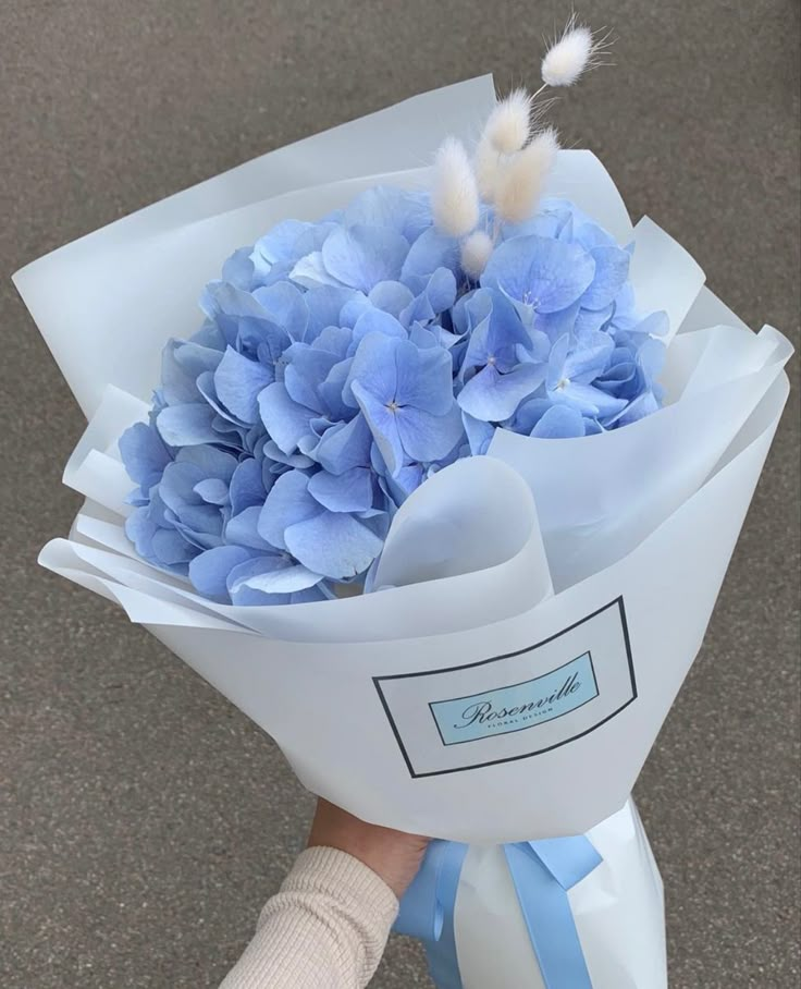 a person holding a bouquet of blue flowers