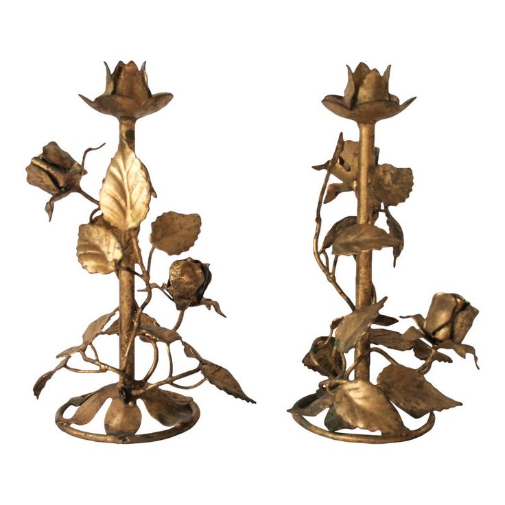 two metal candlesticks with flowers and leaves on them, one has a candle holder in the shape of a flower