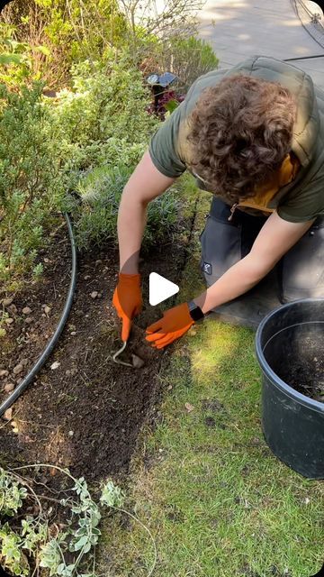 a man with an orange glove is digging in the ground next to a black bucket