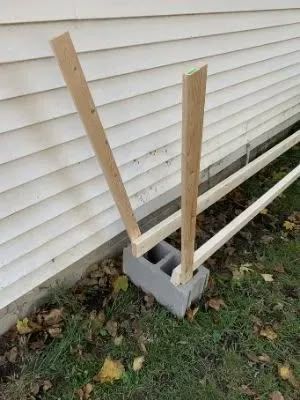 there are two wooden poles sticking out of the ground next to a white house that has fallen leaves on it