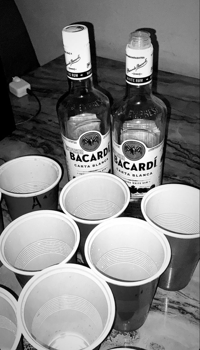 several empty plastic cups sitting on top of a table next to bottles of alcohol and glasses