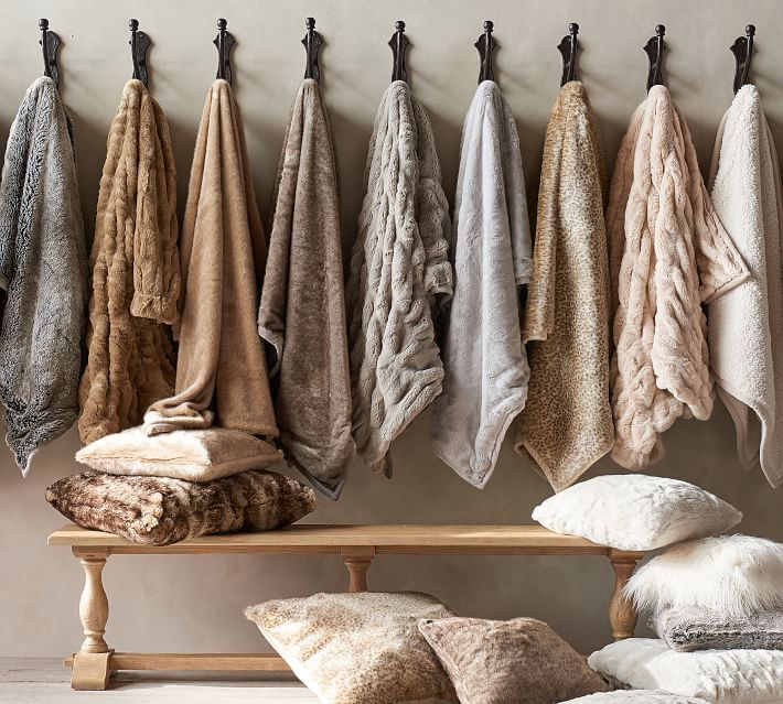 a row of towels hanging on the wall next to a bench with pillows and blankets