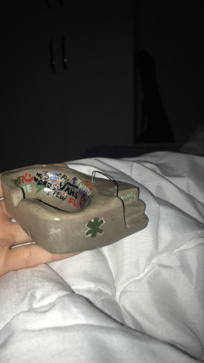 a person's hand is holding an object that looks like a rock with graffiti on it