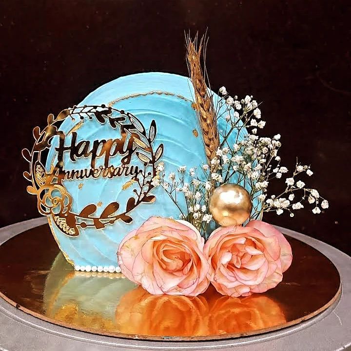 there is a blue cake with flowers on the plate and two roses next to it