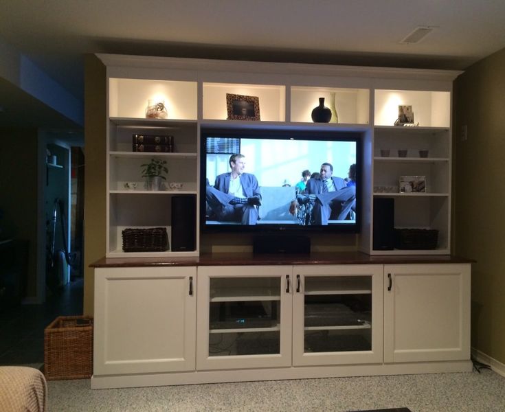 a large entertainment center with two televisions on it's sides and shelves below