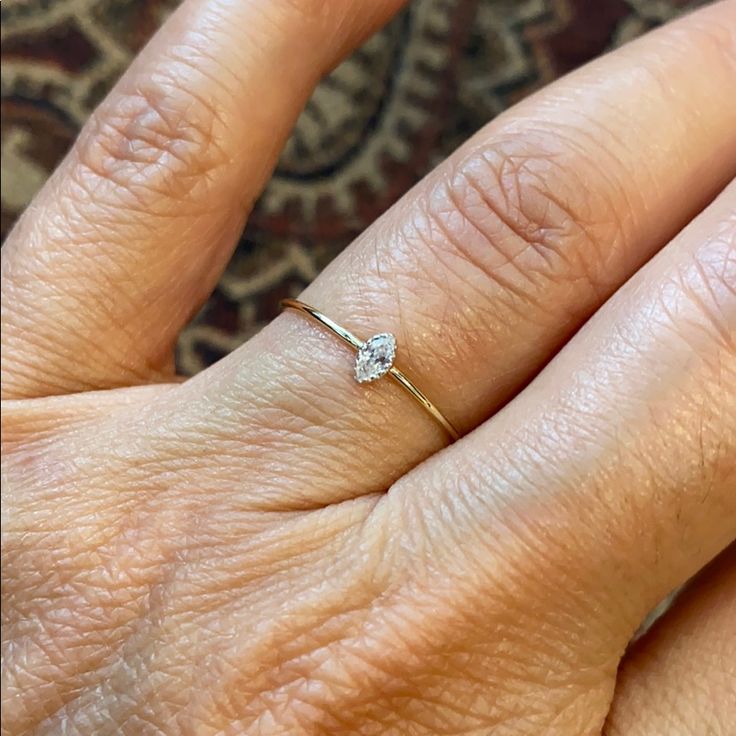 a woman's hand with a diamond ring on top of her left hand,