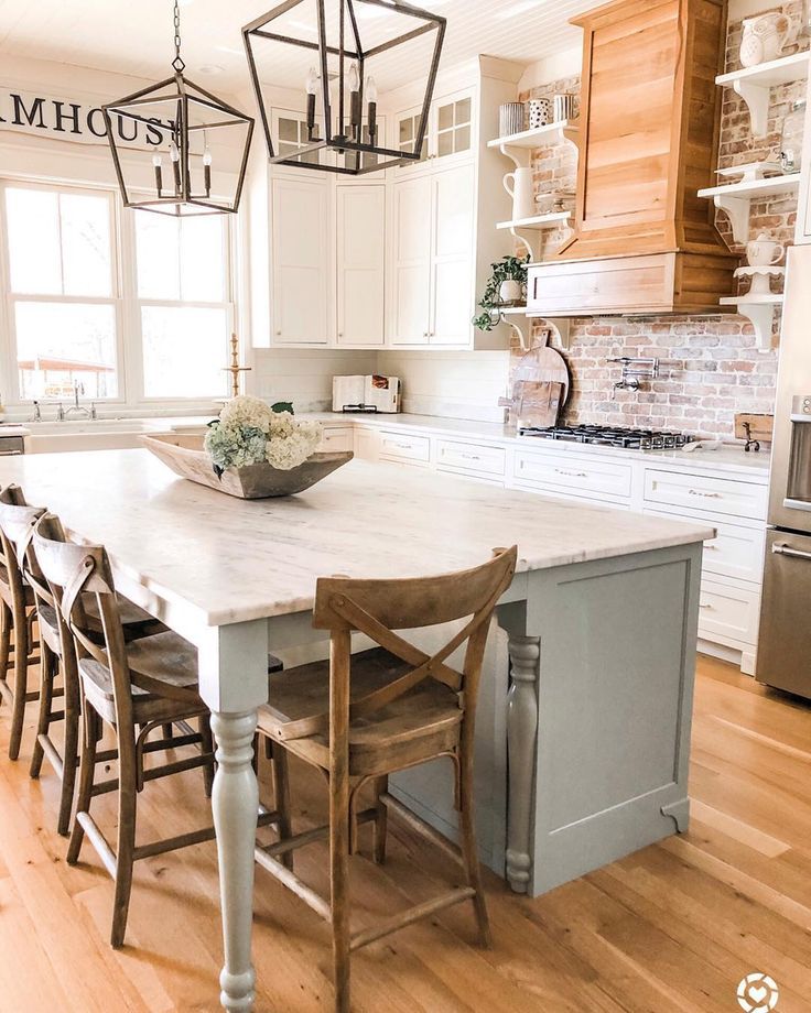 a large kitchen with white cabinets and wooden floors, an island table surrounded by chairs