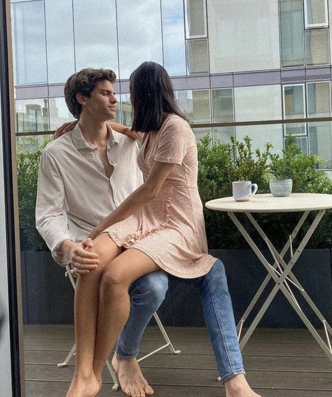 a man and woman sitting on a bench next to each other with their legs crossed