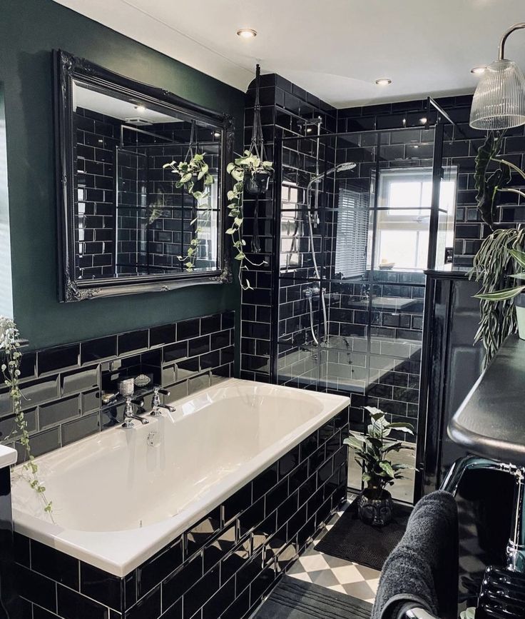 a black and white tiled bathroom with a bathtub, sink, mirror and plants