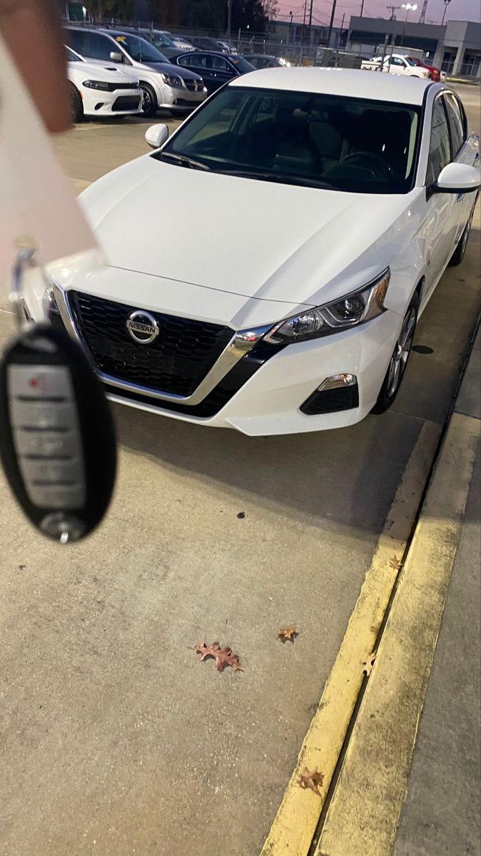 a white car parked on the side of a road next to a parking meter with a person holding a cell phone in front of it