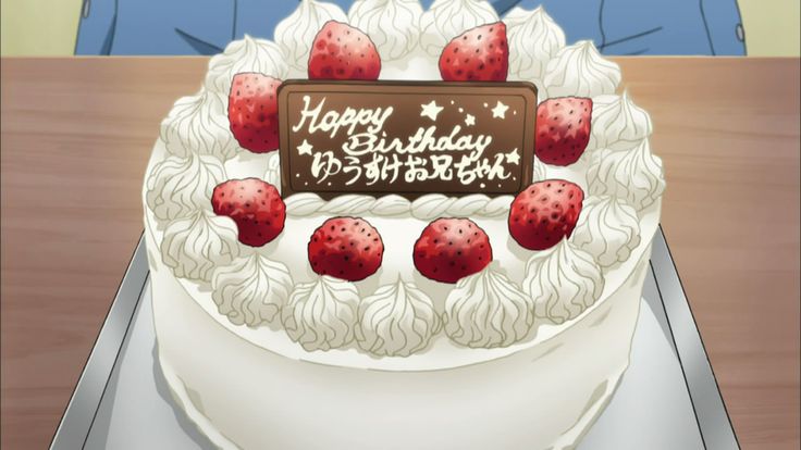 a birthday cake with strawberries on it sitting on top of a table next to a woman