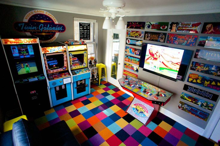 a room filled with arcade machines and colorful carpeted flooring in front of two windows