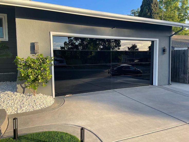 a car is parked in front of a garage with its doors open and gravel around it