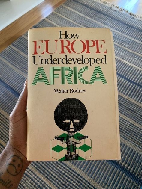 the book how europe developed africa is being held by a person's arm and hand