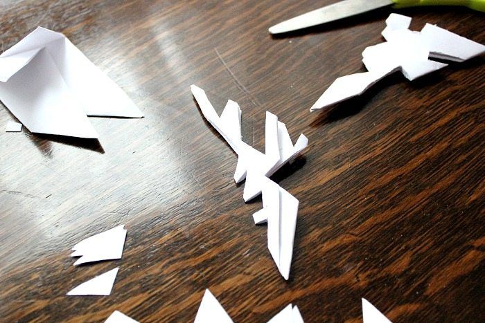 cut out paper snowflakes sitting on top of a wooden table