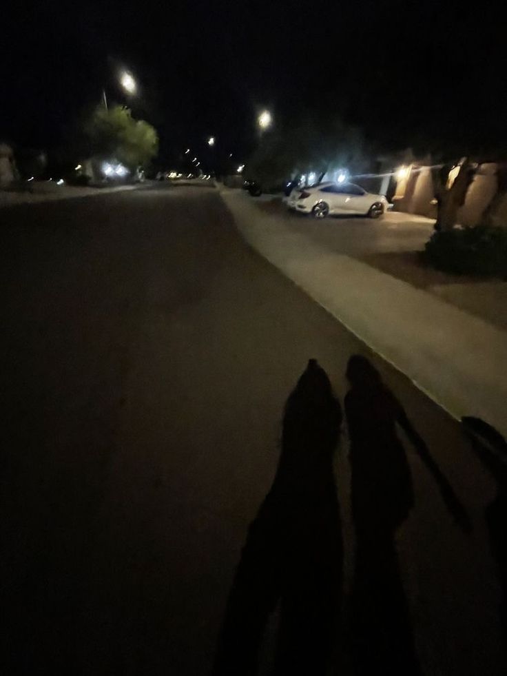 the shadow of two people standing in front of a parking lot at night