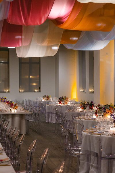 a banquet hall with tables and chairs covered in white tablecloths, decorated with colorful streamers