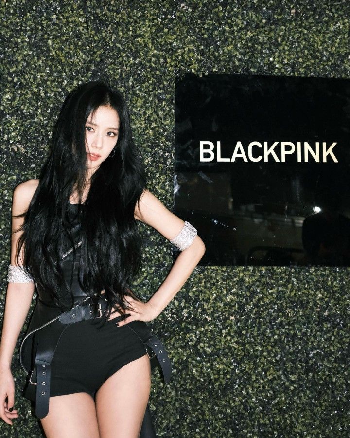 a woman with long black hair standing in front of a sign that says blackpink