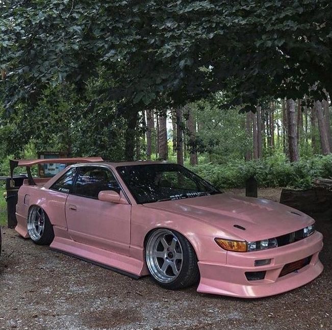 a pink sports car parked in the woods