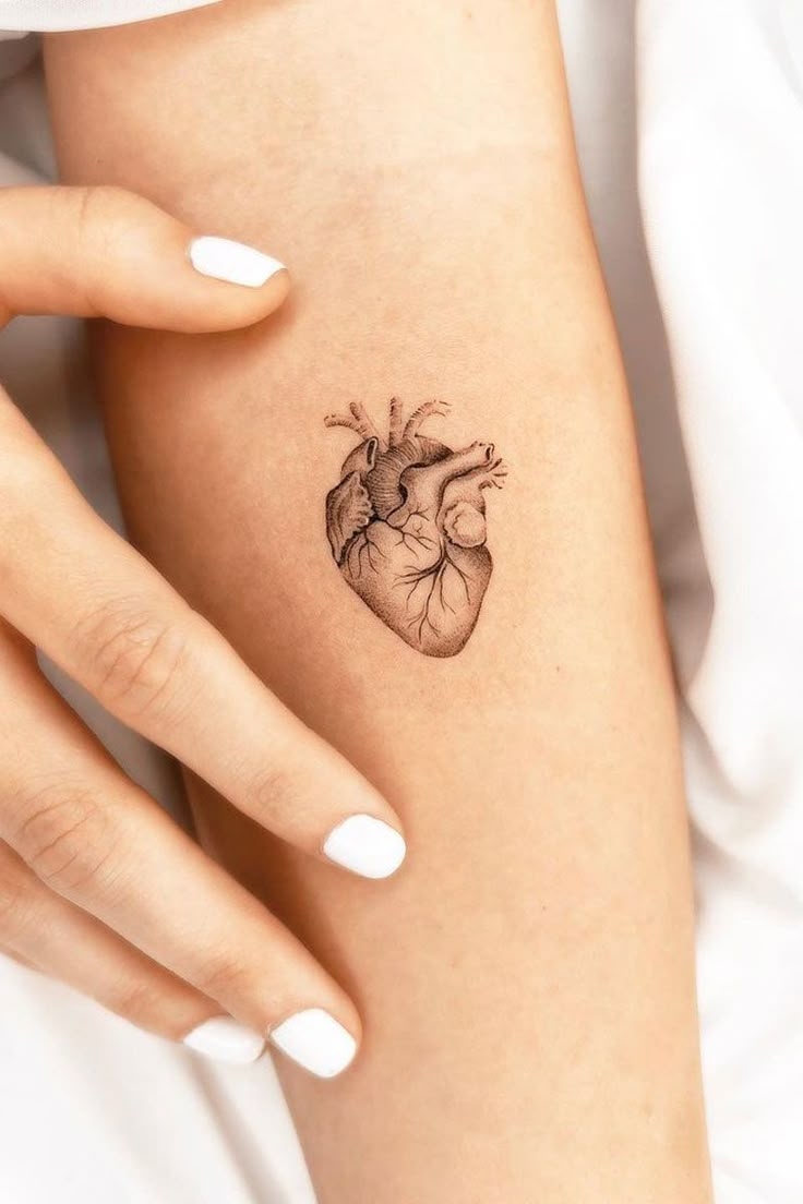 a woman's arm with a small heart tattoo on the left side of her body