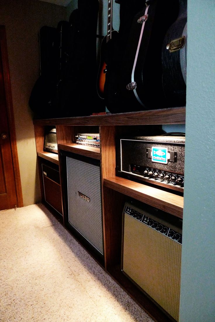 an array of guitars and amps sit on shelves in a room with carpeted flooring