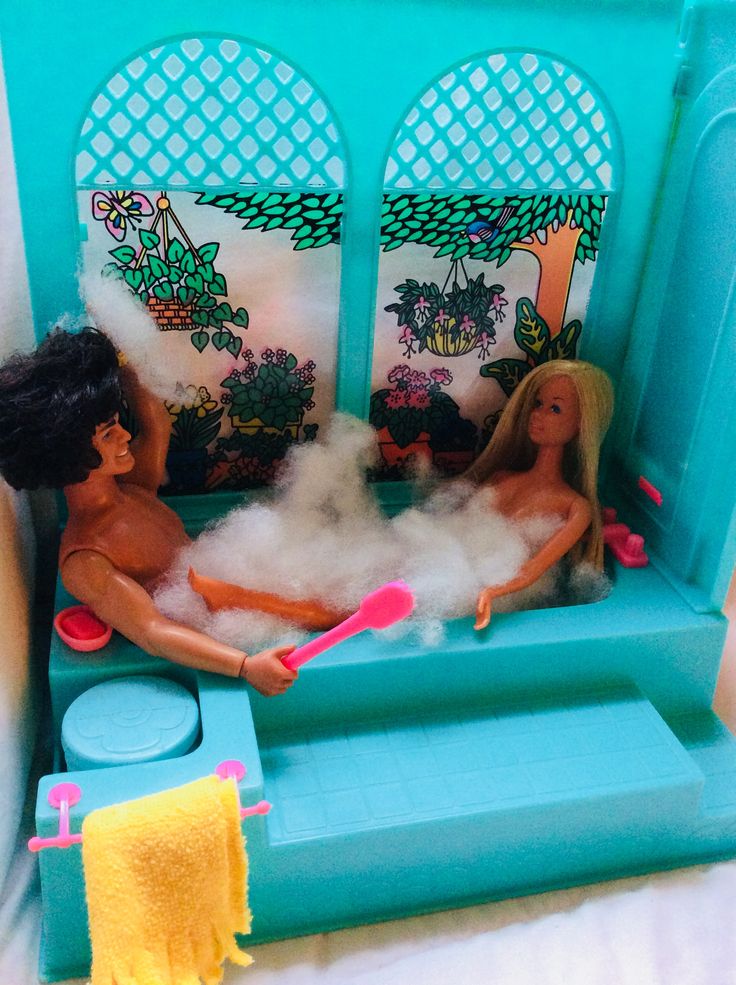 two dolls are sitting in a toy bathtub