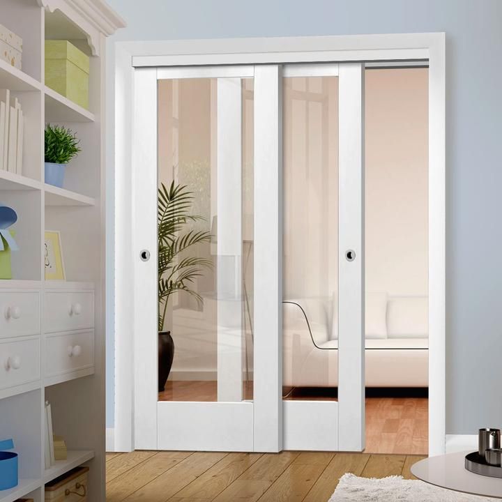 an empty room with white furniture and glass doors