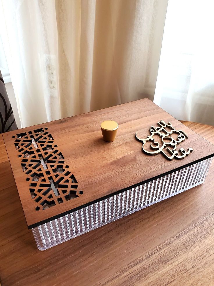 a wooden box sitting on top of a table next to a cup and saucer