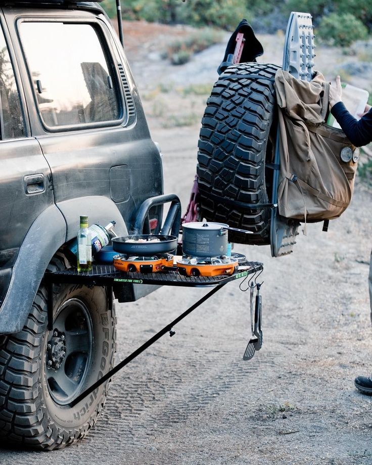 a man standing next to a truck with a large tire on it's back