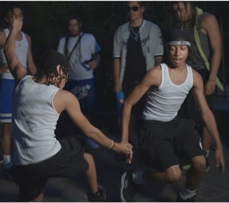 two men playing tennis in front of a group of people wearing white shirts and black shorts