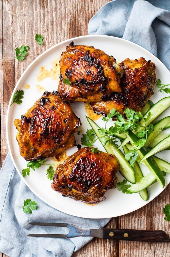 three pieces of chicken on a plate with cucumbers