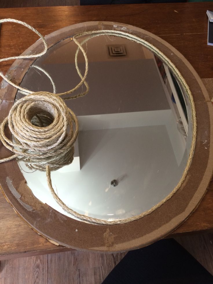 a round glass table with some twine on it and a mirror in the middle