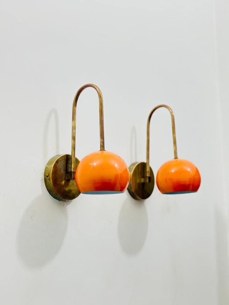 three orange lights hanging from hooks on a wall