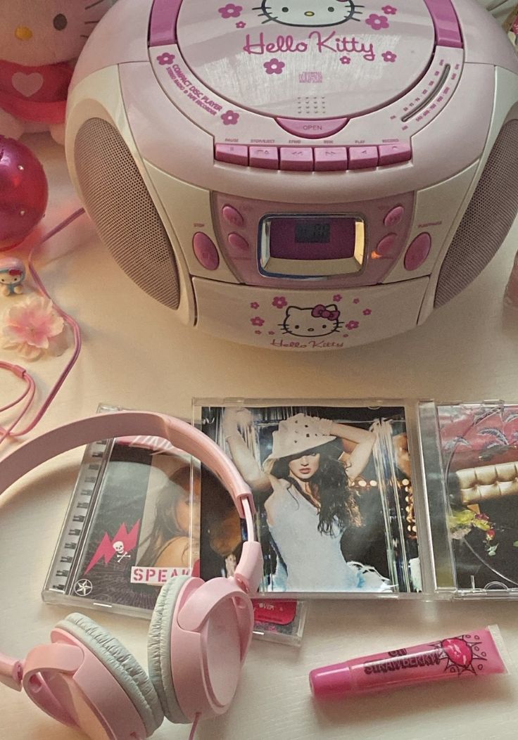 a hello kitty boombox with headphones, cd player and pictures on the table