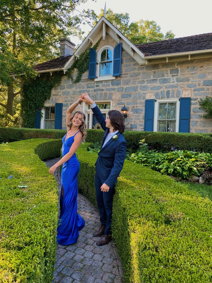 a woman in a blue dress standing next to a man in a suit