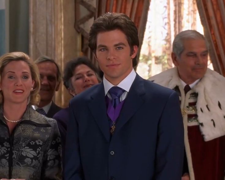 a man in a suit and tie standing next to a woman with other people behind him