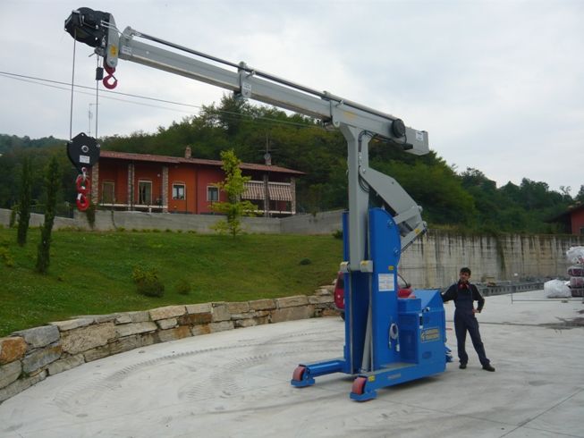 a man standing next to a blue machine on top of a cement slab in front of a building