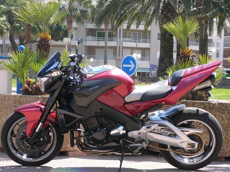 a red and black motorcycle parked in front of palm trees