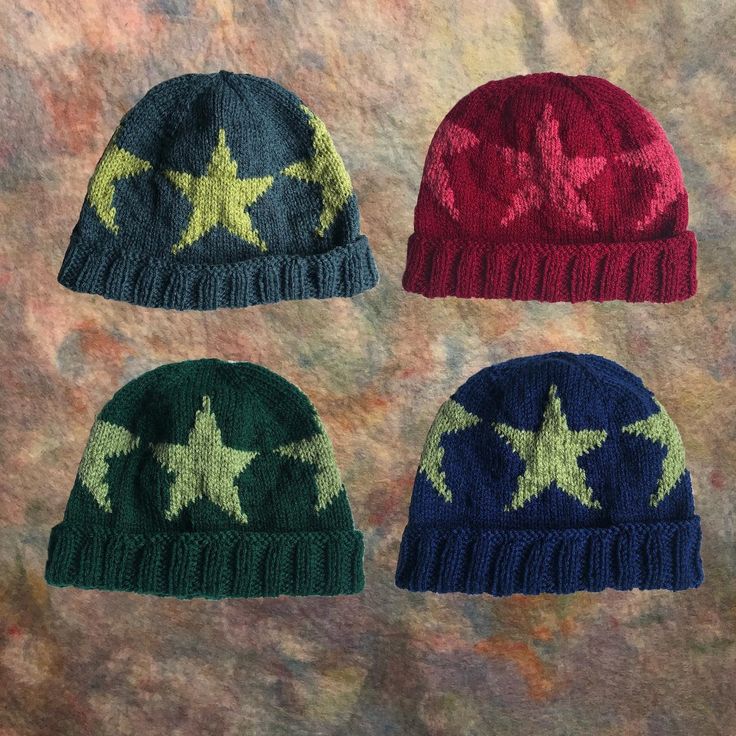 three knitted hats with stars on them, one is red, one is green and the other is blue