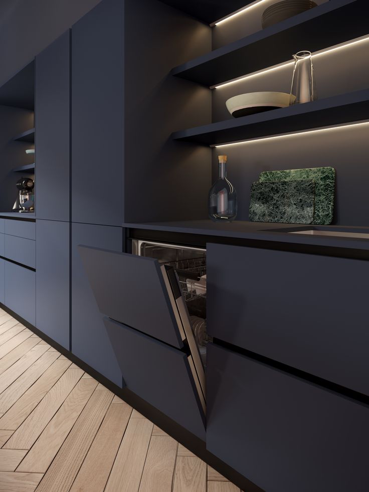 a kitchen with dark blue cabinets and wooden flooring is lit by recessed lighting