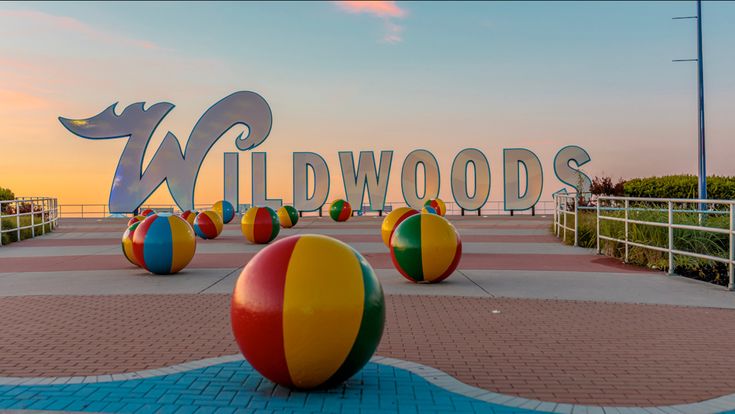 colorful beach balls sitting in front of the wildwoods sign at sunset or dawn