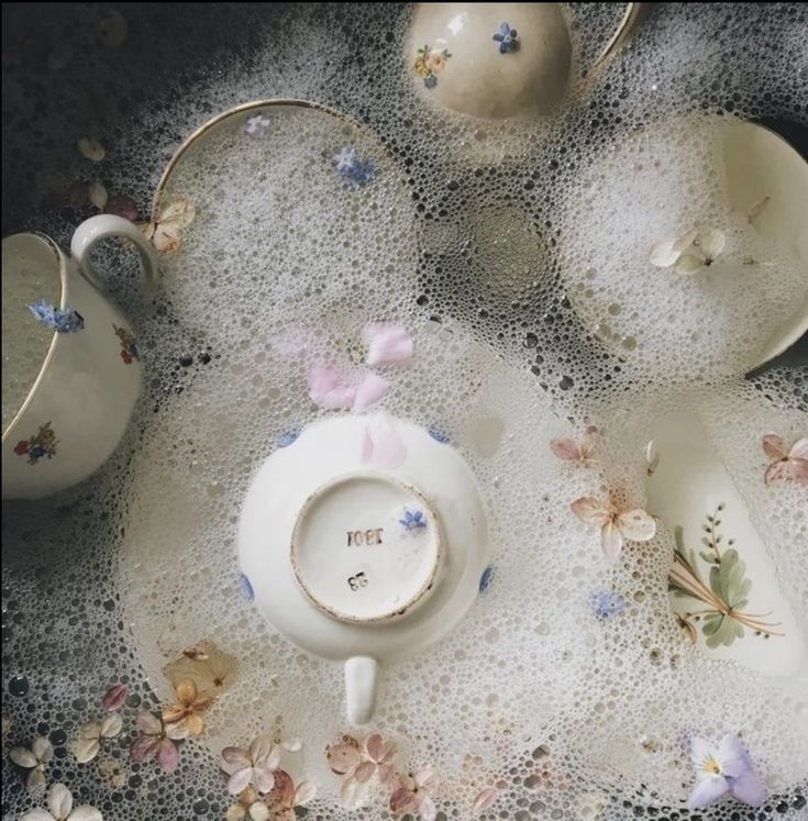 an arrangement of tea cups and saucers with sprinkles on them