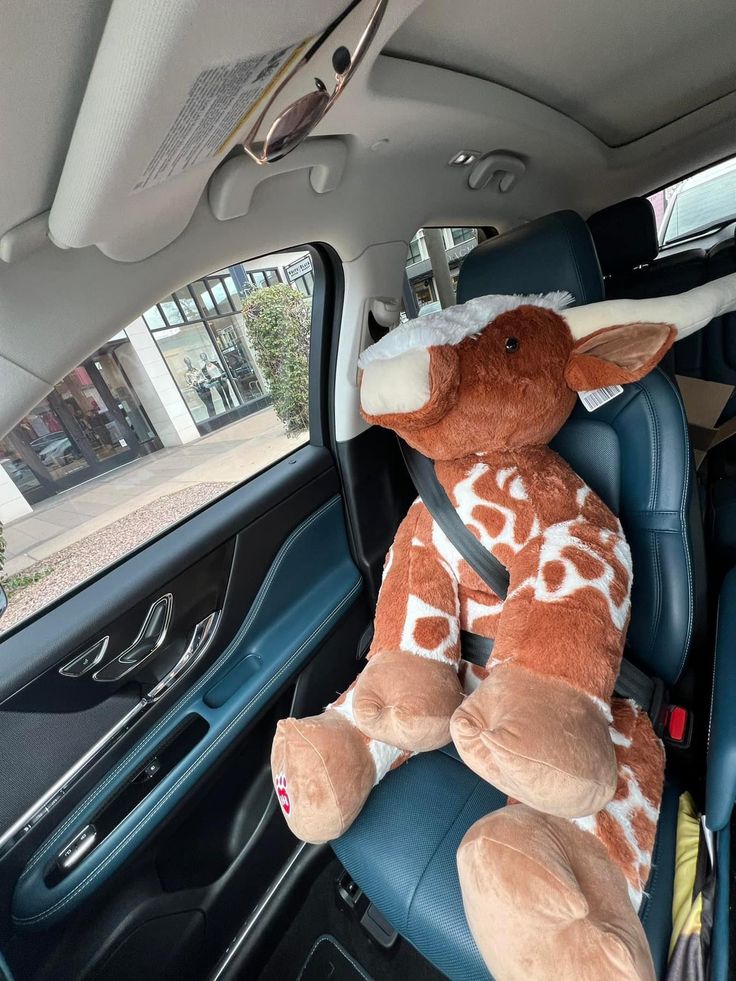 a stuffed giraffe sitting in the back seat of a car