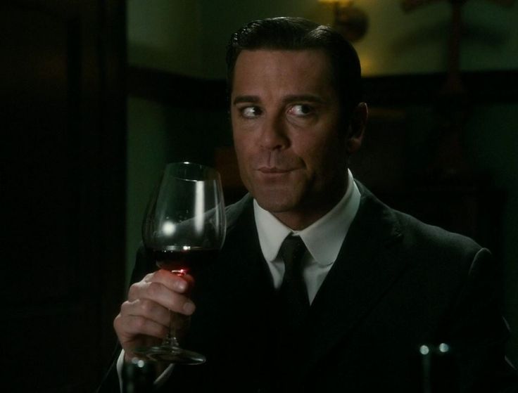 a man in a suit holding a glass of wine