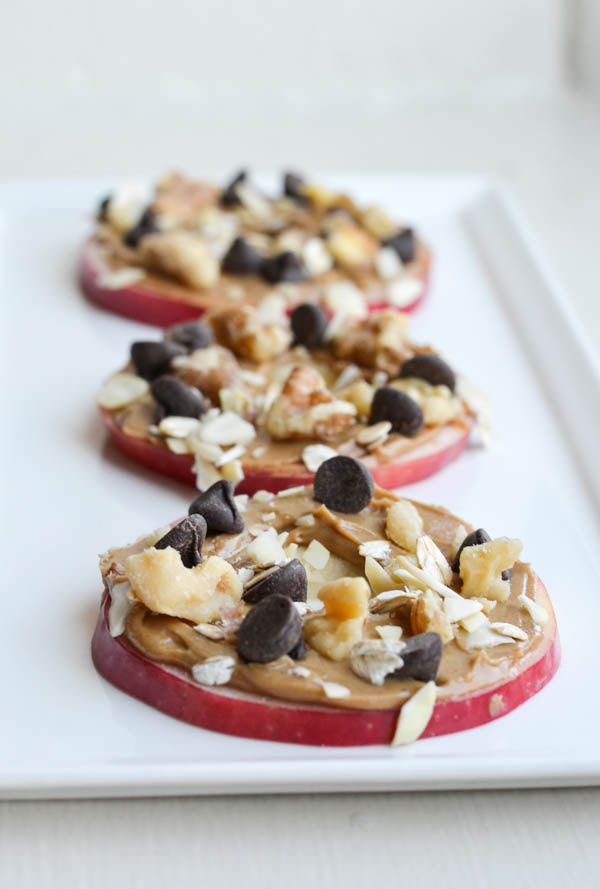 three pieces of fruit with nuts and chocolate chips on them sitting on a white surface