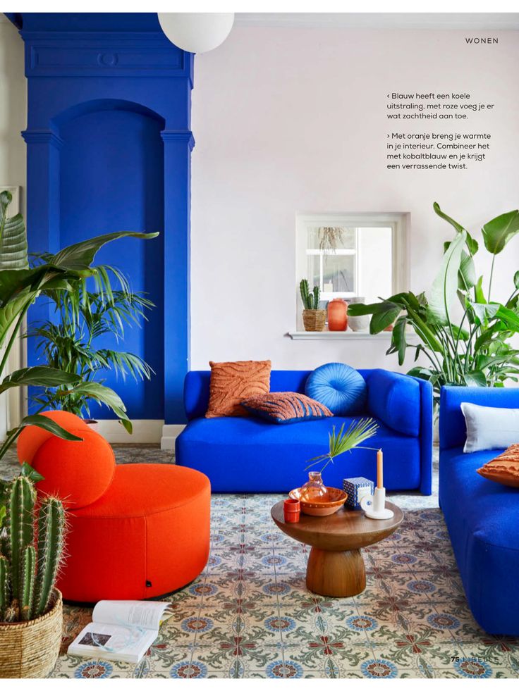 a living room filled with blue couches and potted plants