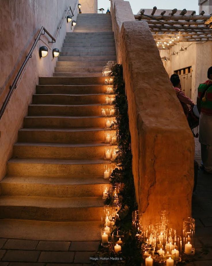 candles are lit on the steps leading up to an outdoor area with stone walls and stairs