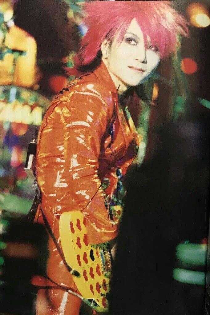 a man with pink hair and piercings standing in front of a casino machine