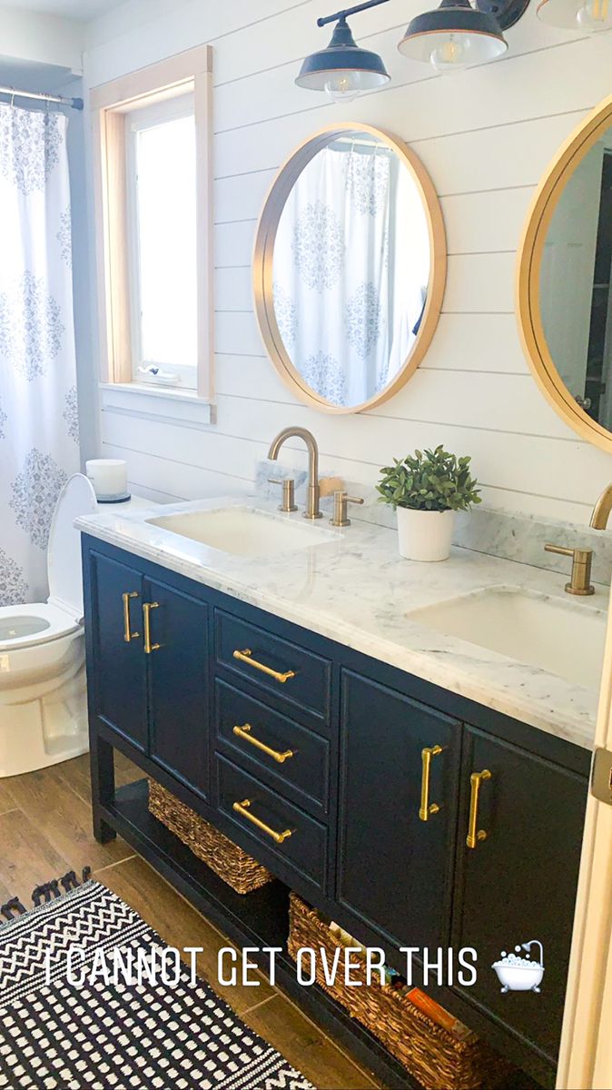 a bathroom with two round mirrors above the sink and a rug on the floor next to it